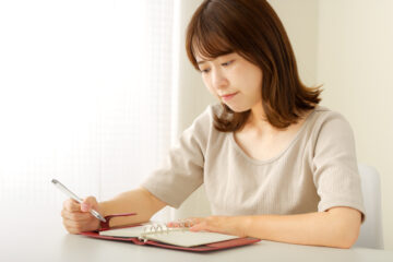 不安げな顔で日記を書く女性