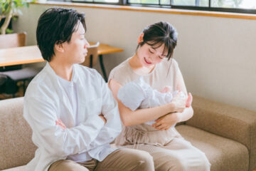 赤ちゃんをあやす女性と眺める男性