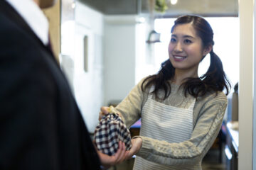 玄関でお弁当を夫に渡す妻